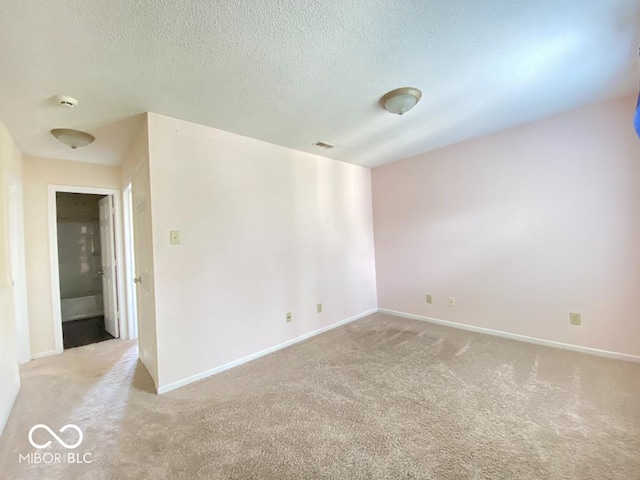 empty room featuring a textured ceiling, carpet flooring, visible vents, and baseboards