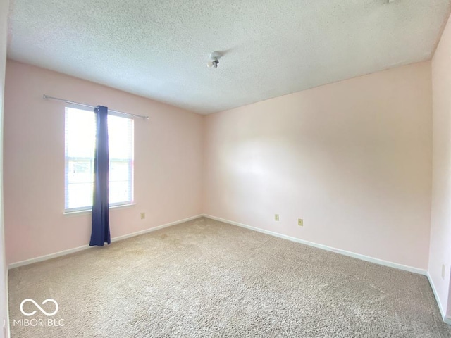 carpeted empty room featuring baseboards and a textured ceiling