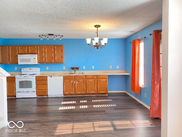 kitchen featuring dark wood-style floors, light countertops, a sink, a chandelier, and white appliances