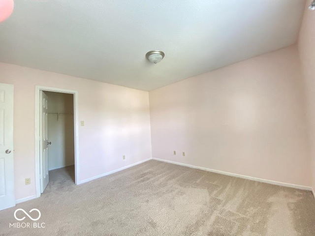 unfurnished bedroom with carpet, a spacious closet, baseboards, and a closet