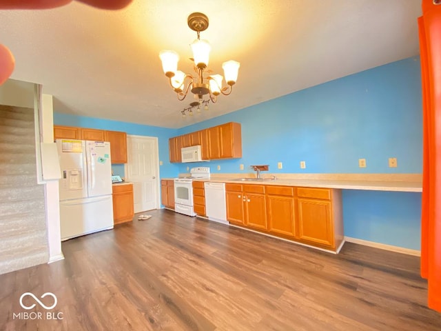 kitchen featuring white appliances, dark wood-style flooring, an inviting chandelier, light countertops, and a sink