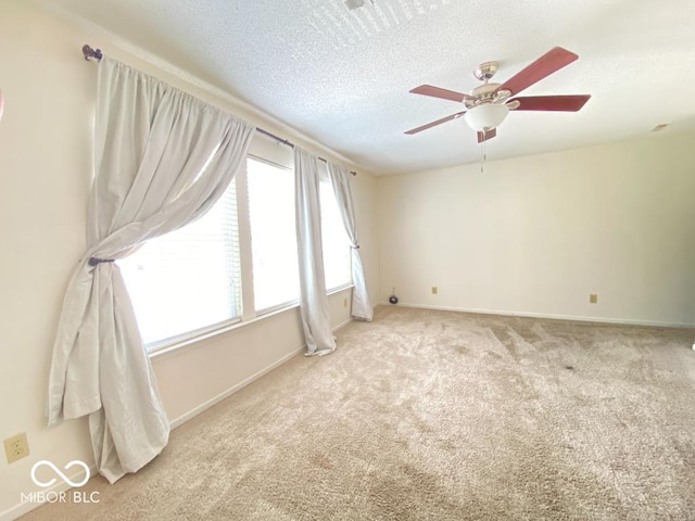 empty room featuring a textured ceiling, ceiling fan, carpet flooring, and baseboards