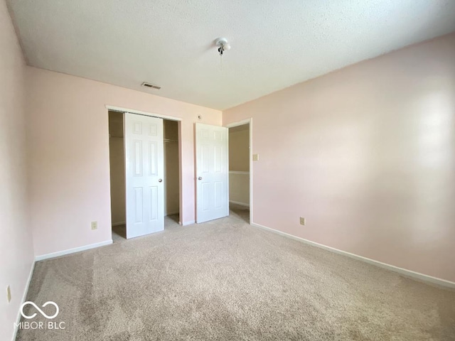 unfurnished bedroom featuring baseboards, visible vents, a textured ceiling, carpet flooring, and a closet