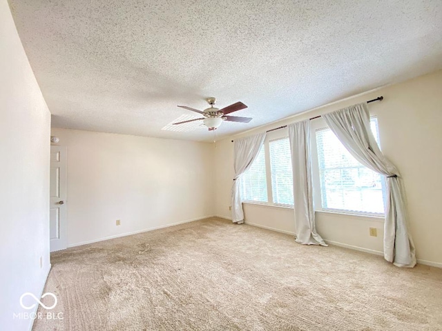 carpeted empty room featuring ceiling fan, a textured ceiling, and baseboards