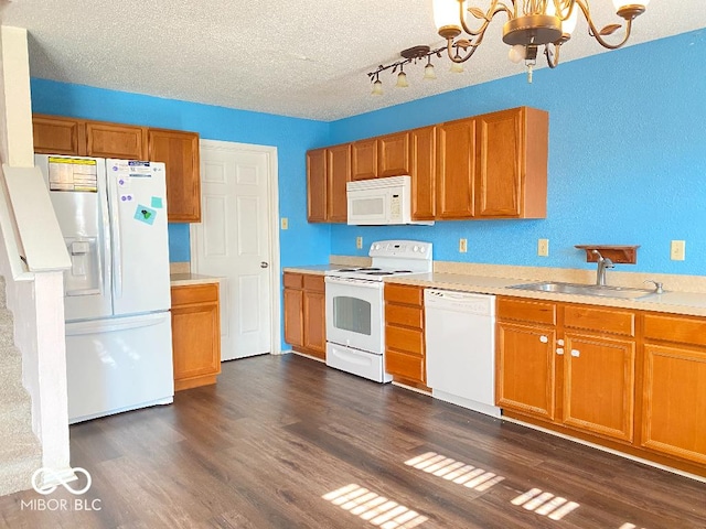 kitchen with white appliances, dark wood-type flooring, a sink, and an inviting chandelier