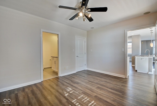 spare room with baseboards, dark wood-style floors, and a ceiling fan