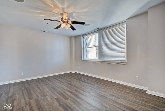 unfurnished room featuring dark wood-style floors, visible vents, a ceiling fan, and baseboards