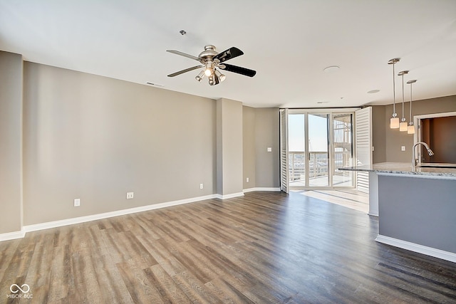 unfurnished living room with visible vents, baseboards, floor to ceiling windows, wood finished floors, and a sink