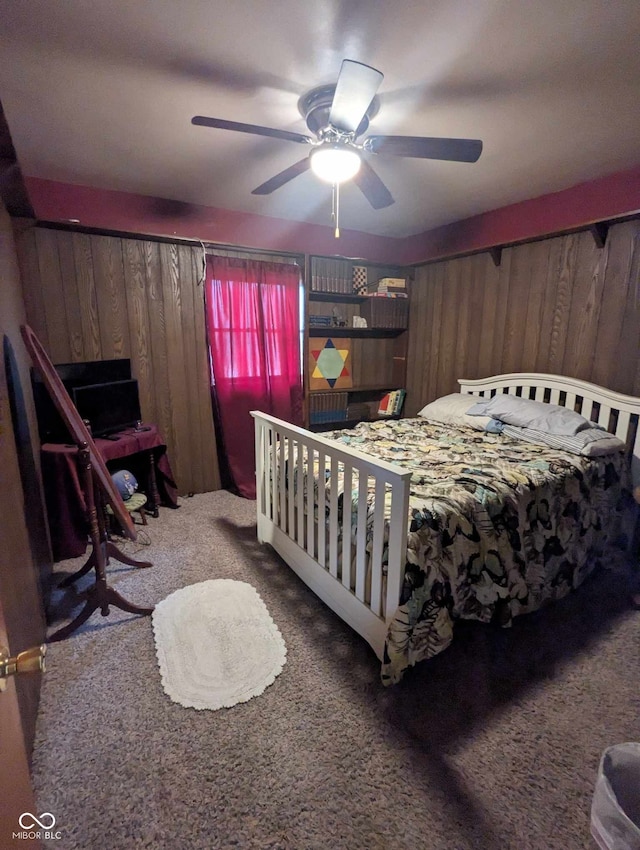 bedroom with carpet floors, wood walls, and a ceiling fan