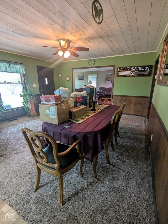 dining space with carpet floors, a wainscoted wall, wood ceiling, and wooden walls