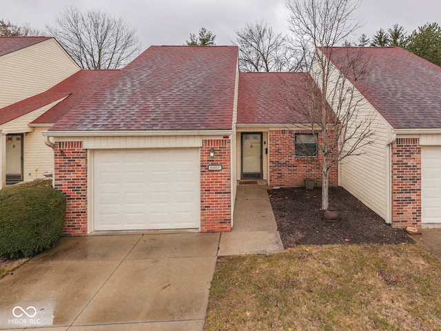 view of front facade featuring concrete driveway, a garage, brick siding, and roof with shingles