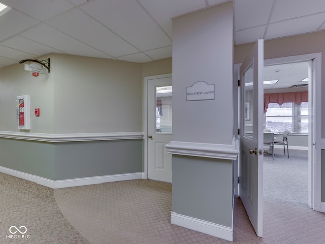 interior space featuring baseboards, a paneled ceiling, and carpet