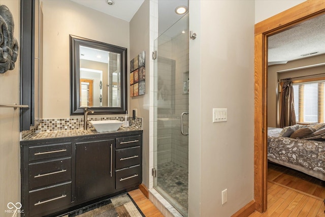 full bathroom with a stall shower, visible vents, wood finished floors, and ensuite bathroom