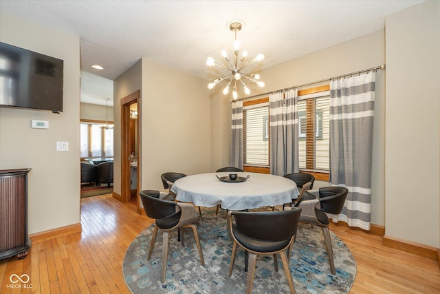 dining space with baseboards, an inviting chandelier, and light wood finished floors