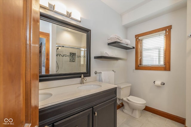 bathroom with toilet, a stall shower, a sink, double vanity, and baseboards