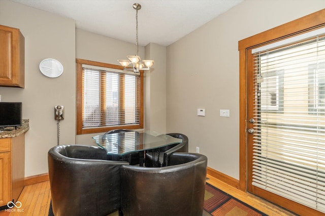 dining space with light wood-style flooring, a notable chandelier, and baseboards