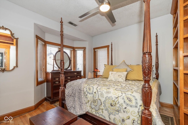 bedroom with a ceiling fan, baseboards, visible vents, light wood-style floors, and a textured ceiling