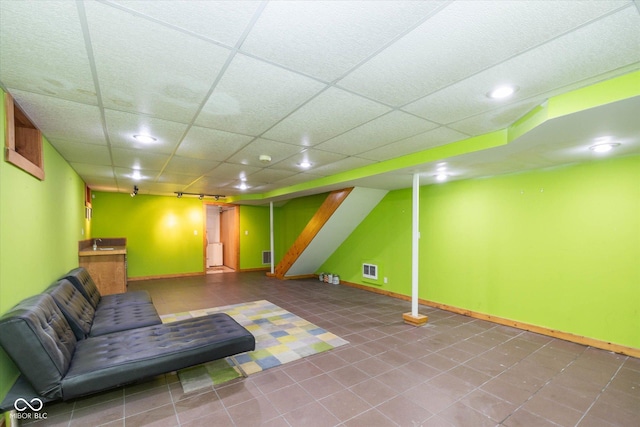 interior space featuring baseboards, a paneled ceiling, and tile patterned flooring