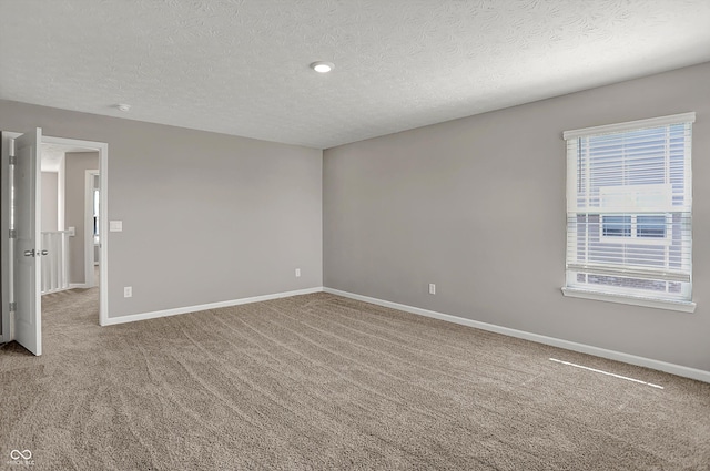 empty room featuring carpet, baseboards, and a textured ceiling