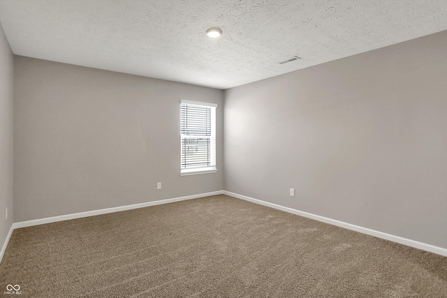 carpeted spare room with a textured ceiling, baseboards, and visible vents