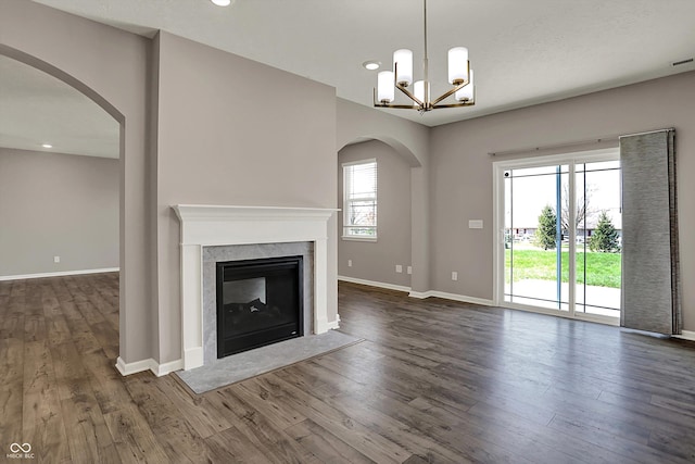 unfurnished living room with baseboards, arched walkways, a high end fireplace, and dark wood finished floors