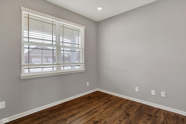 unfurnished room featuring baseboards and dark wood finished floors