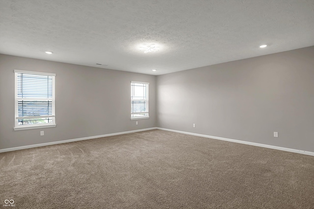 carpeted empty room featuring baseboards, recessed lighting, and a textured ceiling