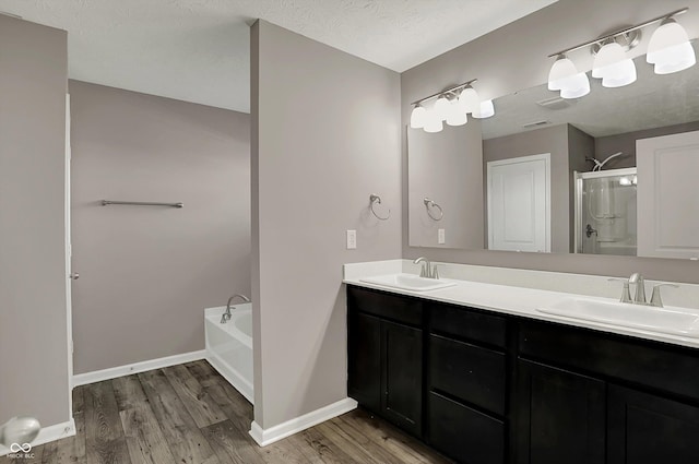 bathroom featuring a shower stall, a bath, wood finished floors, and a sink