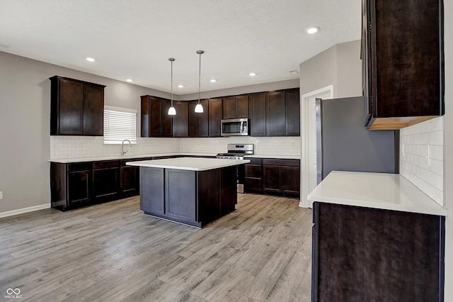 kitchen with a center island, dark brown cabinets, light wood-style floors, stainless steel appliances, and a sink