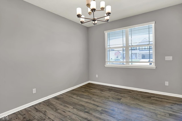 unfurnished room with dark wood-type flooring, baseboards, and an inviting chandelier