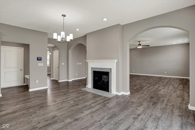 unfurnished living room with dark wood-style flooring, ceiling fan, baseboards, and a fireplace