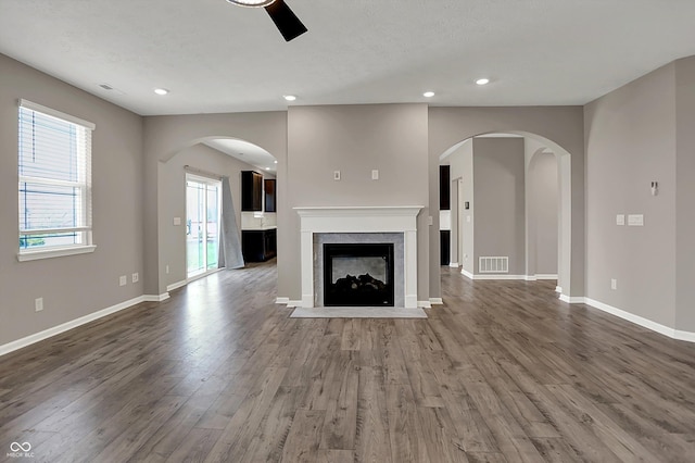 unfurnished living room with ceiling fan, a fireplace with flush hearth, recessed lighting, wood finished floors, and baseboards