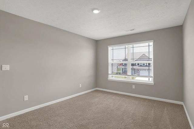 spare room with carpet flooring, baseboards, and visible vents