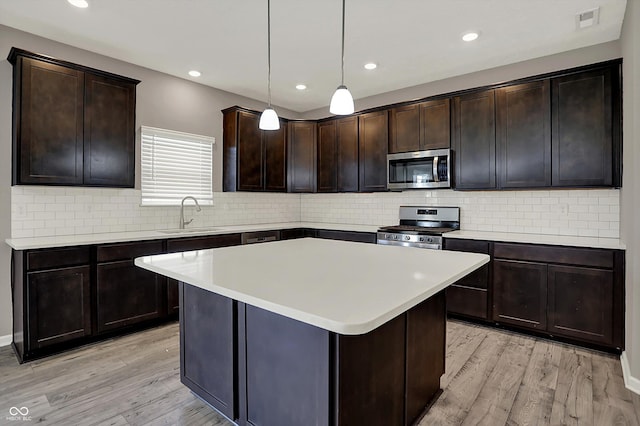 kitchen with stainless steel appliances, light wood-style floors, visible vents, and a sink