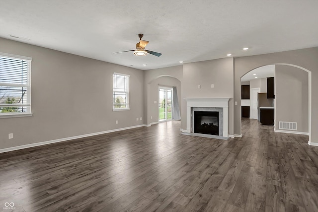 unfurnished living room with ceiling fan, baseboards, dark wood finished floors, and visible vents