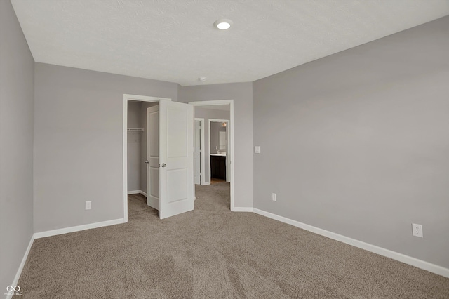 unfurnished bedroom with a closet, a walk in closet, baseboards, and carpet floors
