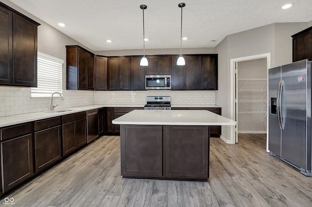 kitchen featuring light wood-type flooring, dark brown cabinets, a kitchen island, appliances with stainless steel finishes, and a sink