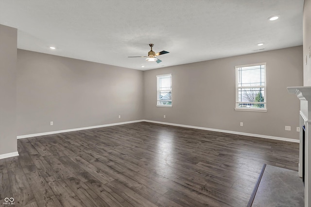 spare room with dark wood-style flooring, baseboards, recessed lighting, a fireplace, and a ceiling fan