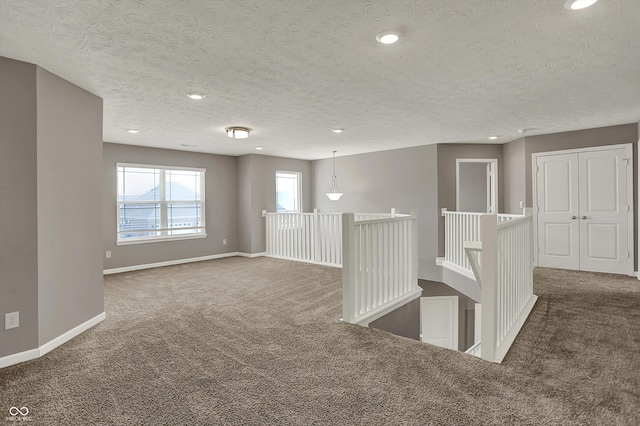 empty room featuring a textured ceiling, baseboards, carpet, and recessed lighting
