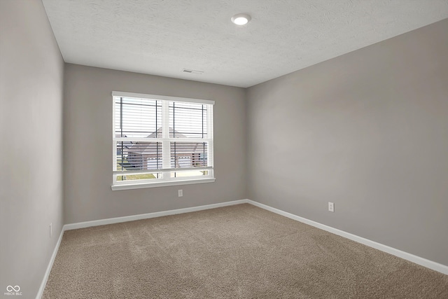 carpeted empty room with visible vents, baseboards, and a textured ceiling