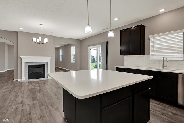 kitchen with tasteful backsplash, light countertops, a sink, open floor plan, and light wood finished floors