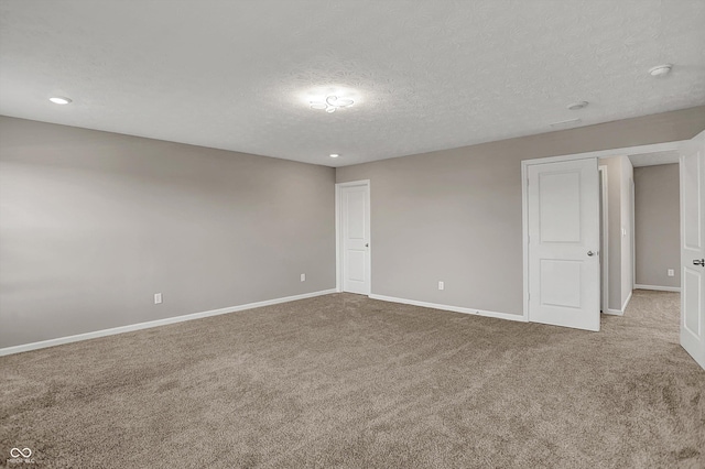 spare room with a textured ceiling, baseboards, and carpet