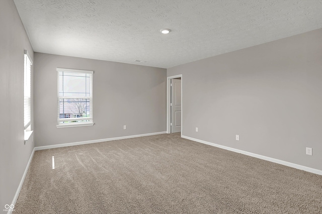 carpeted empty room featuring baseboards and a textured ceiling