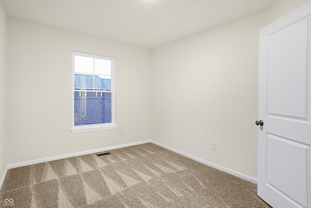 carpeted spare room featuring visible vents and baseboards