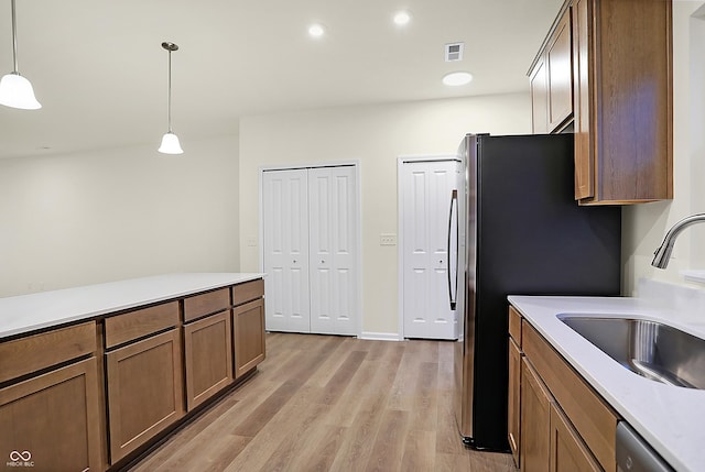 kitchen featuring light wood-type flooring, visible vents, pendant lighting, a sink, and stainless steel appliances