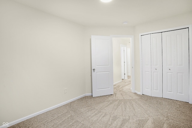 unfurnished bedroom featuring a closet, baseboards, and light colored carpet