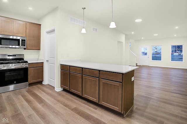 kitchen featuring visible vents, a peninsula, stainless steel appliances, and light countertops