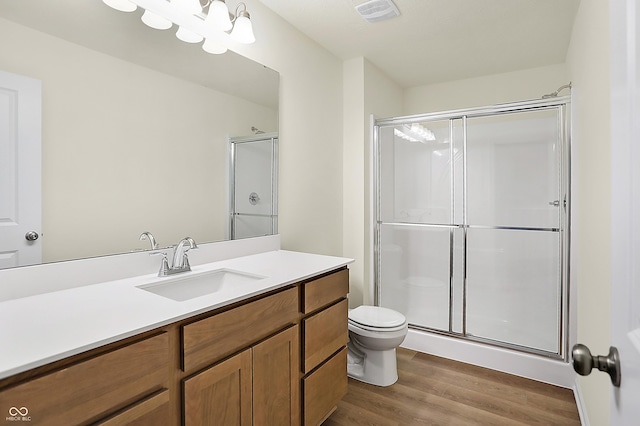 full bath with visible vents, toilet, a stall shower, wood finished floors, and vanity