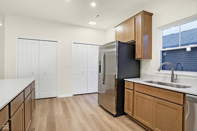 kitchen featuring visible vents, appliances with stainless steel finishes, light wood-type flooring, and a sink