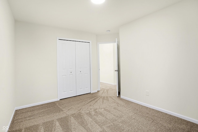 unfurnished bedroom featuring a closet, baseboards, and carpet floors